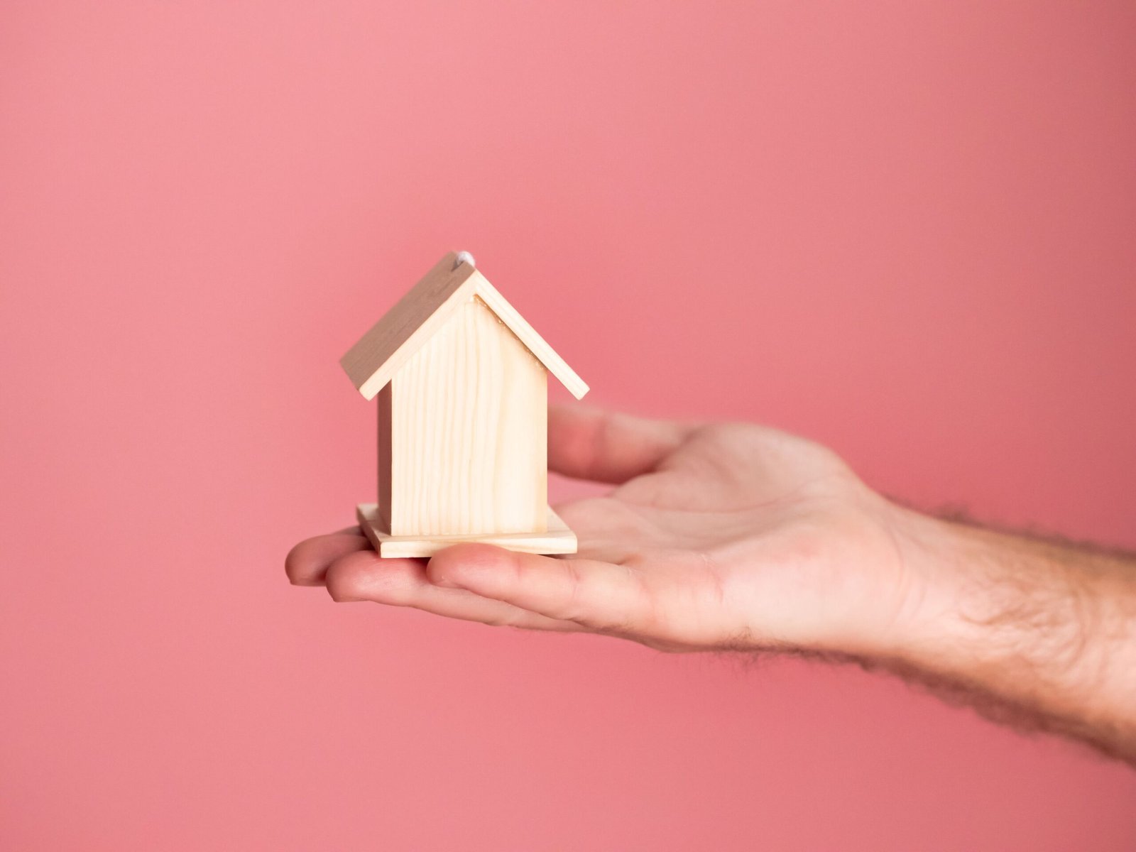 A person is holding a small house to imply house loan