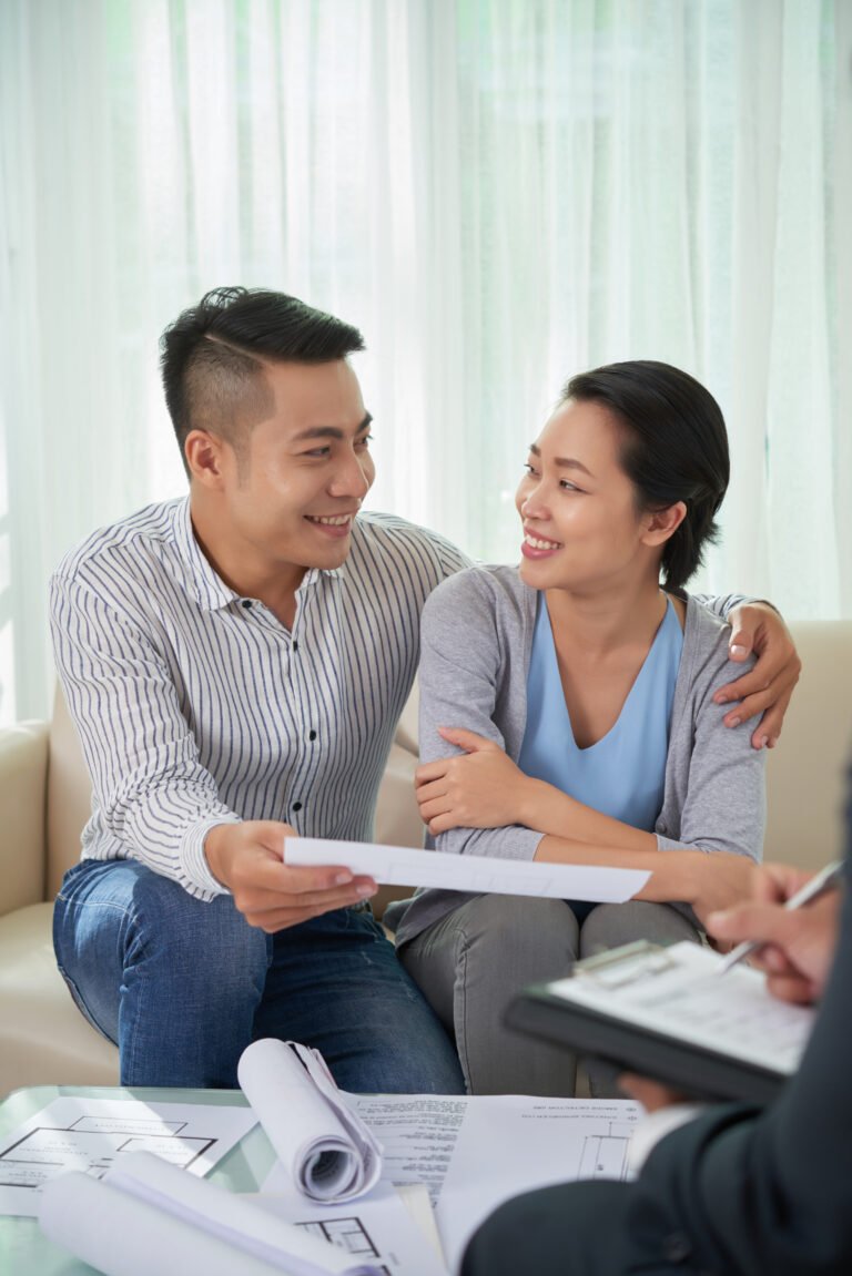 Couple smiling while reviewing emergency loan documents with a loan adviser